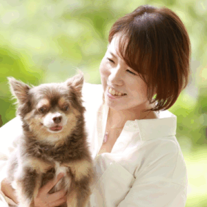 女性が小型犬を抱いて笑顔で見つめている写真