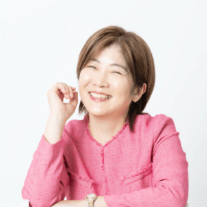 「ピンク色のジャケットを着た女性が笑顔を向けている写真