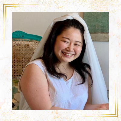 白いベールをかぶり、優しい笑顔で座っている女性の写真