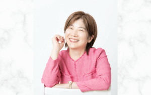 「ピンク色のジャケットを着た女性が笑顔を向けている写真